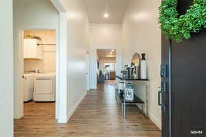 Corridor with light wood-style floors, a high ceiling, recessed lighting, and independent washer and dryer