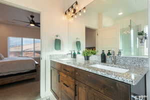 Bathroom featuring double vanity, ensuite bathroom, a stall shower, ceiling fan, and light colored carpet