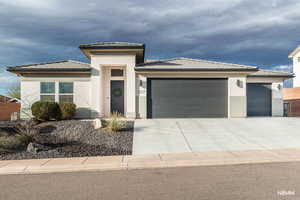 Prairie-style house with a garage, driveway, stucco siding, and a tile roof