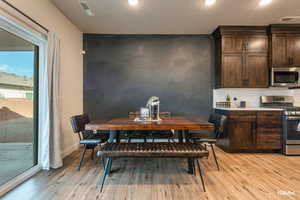 Dining area featuring light wood finished floors, an accent wall, and recessed lighting