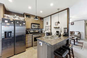 Kitchen with stainless steel appliances, dark countertops, a breakfast bar, hanging light fixtures, and open shelves