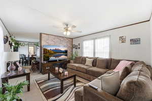 Living area featuring carpet floors, a ceiling fan, and ornamental molding