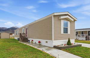 View of side of home with a yard, a storage unit, and a mountain view