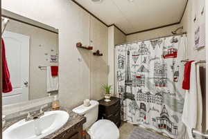 Full bath with crown molding, vanity, and wallpapered walls