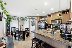 Kitchen with a breakfast bar, hanging light fixtures, gas range, and fridge with ice dispenser