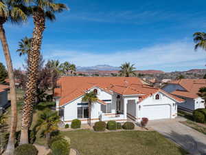 Mediterranean / spanish house featuring a mountain view, a front yard, driveway, and stucco siding