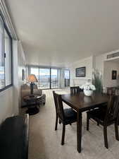 Dining area with light colored carpet, expansive windows, and ornamental molding