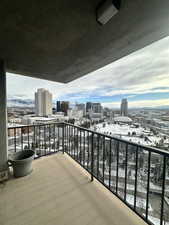 Snow covered back of property with a city view from patio