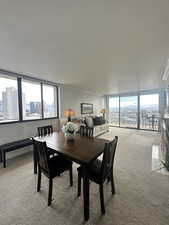 Living room with light carpet, a city view, ornamental molding, and floor to ceiling windows