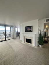 Living room with carpet flooring, crown molding, expansive windows, and a fireplace