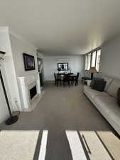 Carpeted living area with a premium fireplace and crown molding