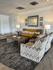 Living room featuring a textured ceiling, crown molding, recessed lighting, and dark wood-type flooring