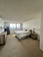 Bedroom with light carpet, crown molding, and a textured ceiling
