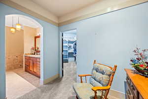Sitting room with light colored carpet, light tile patterned flooring, and arched walkways