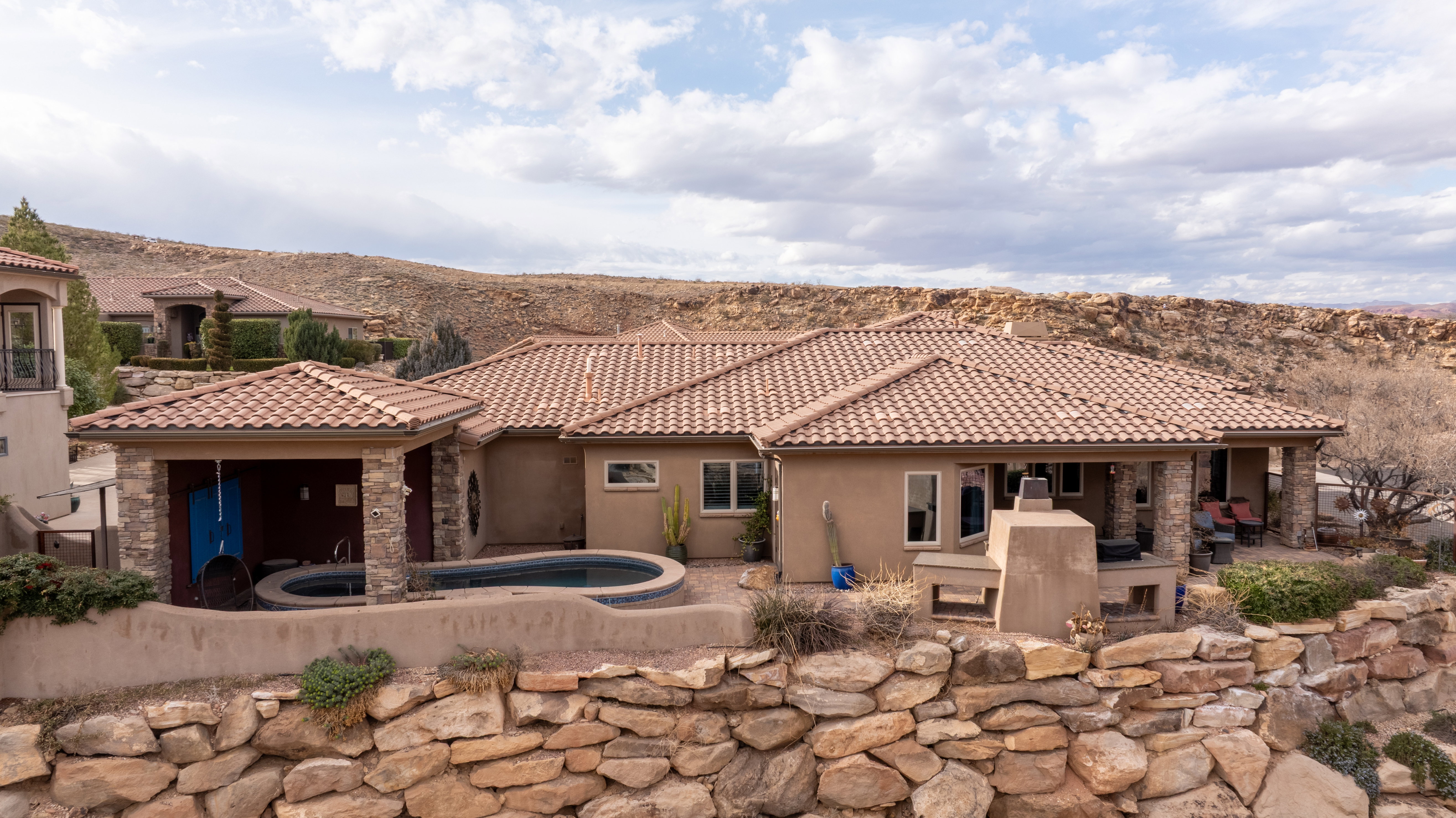 Rear view of house featuring a patio area, stucco siding, stone siding, a fireplace, and an outdoor pool