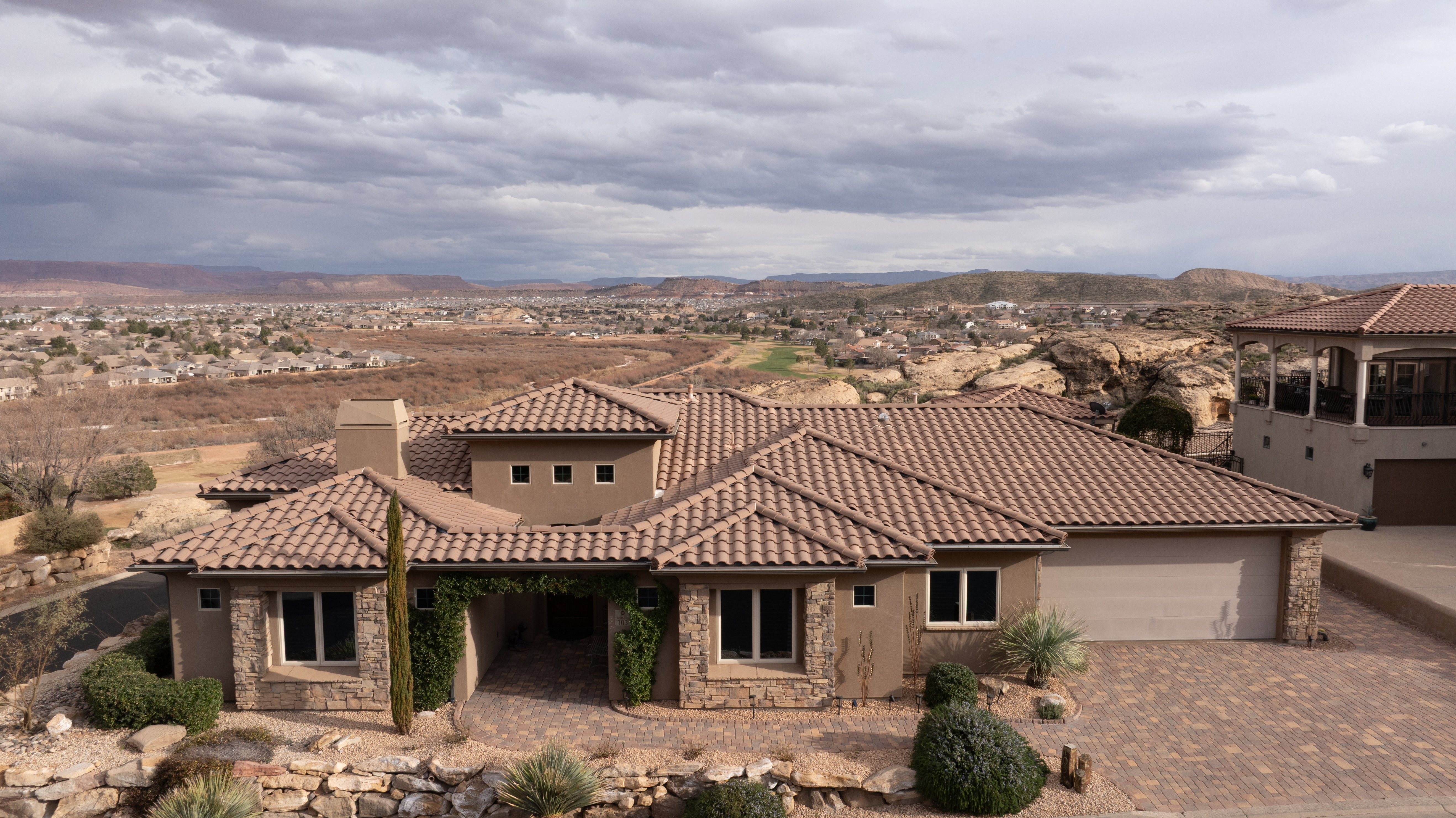 Mediterranean / spanish home with stone siding, a garage, decorative driveway, a chimney, and stucco siding