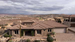 Mediterranean / spanish home with stone siding, a garage, decorative driveway, a chimney, and stucco siding