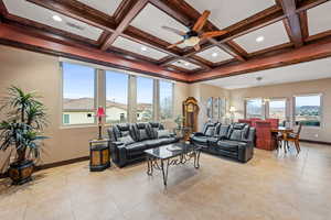 Living area with ceiling fan, coffered ceiling, and light tile patterned flooring