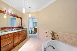 Full bathroom featuring vanity, light tile patterned floors, a bath, and crown molding