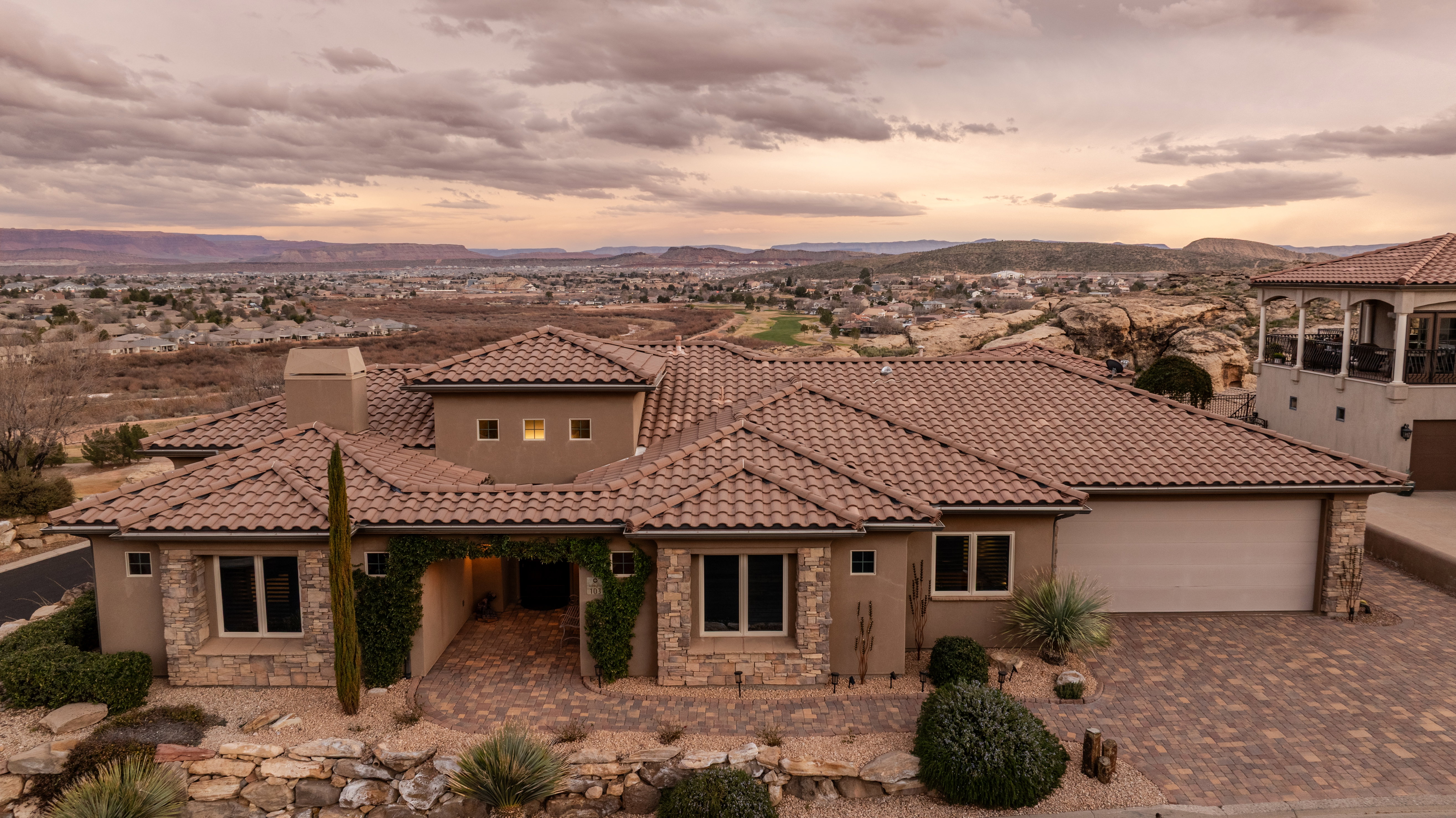 Mediterranean / spanish-style house with stone siding, a chimney, a patio, driveway, and stucco siding