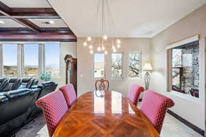 Dining space with coffered ceiling, a chandelier, and light tile patterned flooring