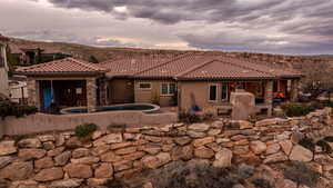 Rear view of house with stone siding, a patio, a fireplace, and stucco siding