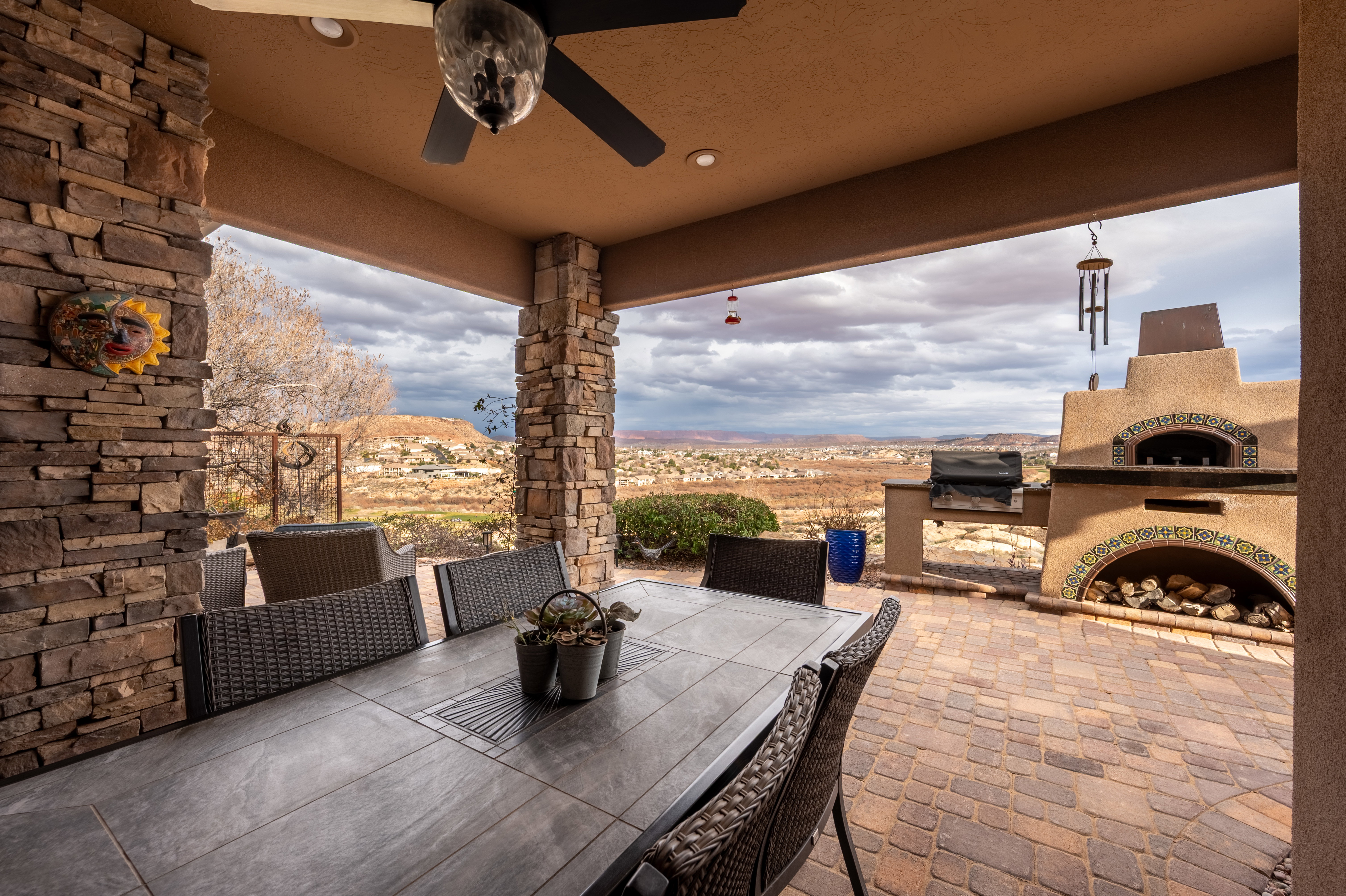 View of patio featuring exterior fireplace, outdoor dining space, a ceiling fan, a grill, and a mountain view