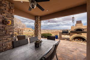 View of patio featuring exterior fireplace, outdoor dining space, a ceiling fan, a grill, and a mountain view