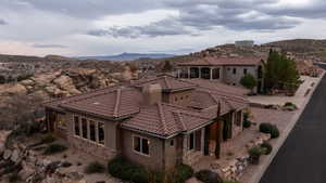 Back of property with stone siding, stucco siding, a tile roof, a mountain view, and a patio area
