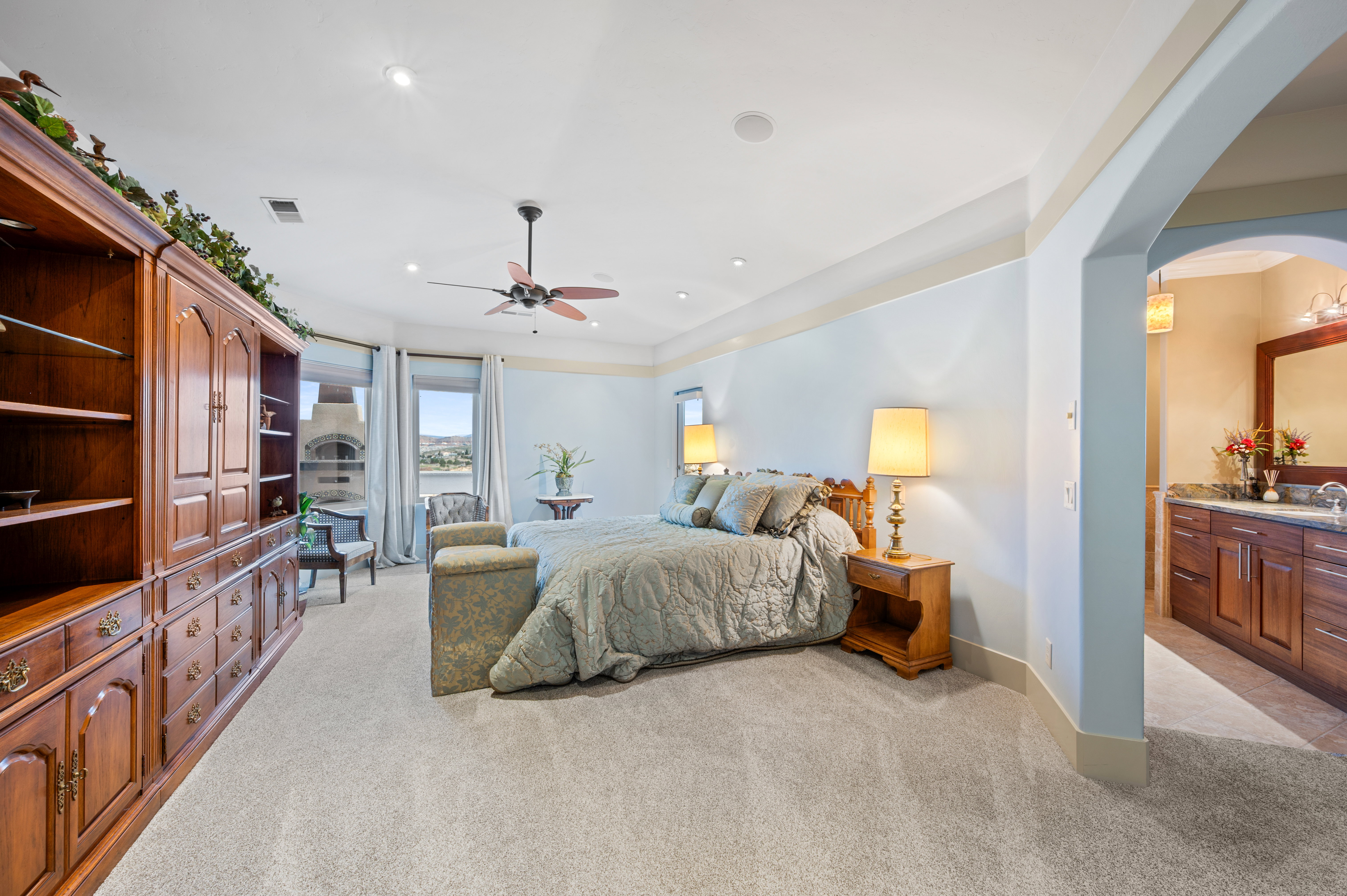 Bedroom featuring light carpet, arched walkways, ceiling fan, and recessed lighting