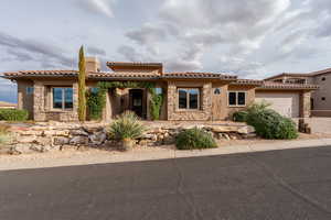 Mediterranean / spanish house featuring stone siding, a garage, stucco siding, and a chimney