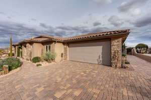 Mediterranean / spanish-style home featuring stone siding, a garage, stucco siding, decorative driveway, and a tiled roof