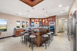 Kitchen featuring arched walkways, a kitchen bar, dark stone counters, a center island, and glass insert cabinets