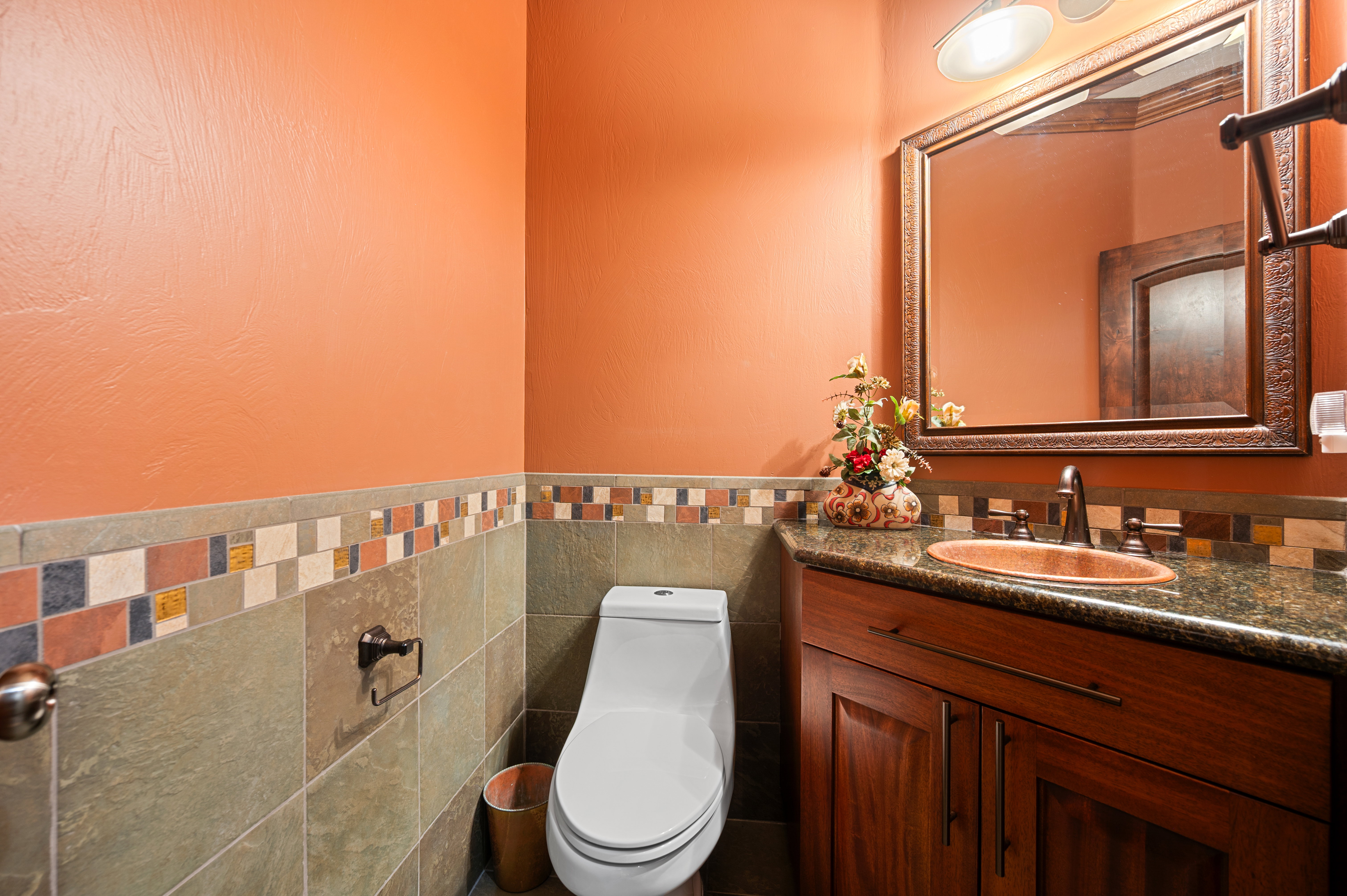 Half bathroom featuring vanity, tile walls, and wainscoting