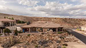 Rear view of property with a patio area, a chimney, stucco siding, and stone siding