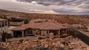 Rear view of property featuring a patio area, a tile roof, and stone siding