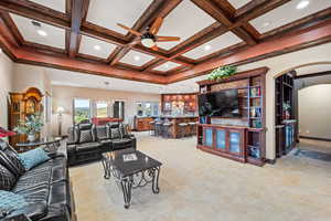 Living area featuring a ceiling fan, arched walkways, a chandelier, coffered ceiling, and light tile patterned flooring