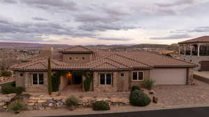 Mediterranean / spanish house featuring stone siding, driveway, an attached garage, and stucco siding