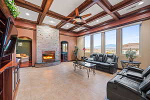 Living room featuring a mountain view, a ceiling fan, arched walkways, a fireplace, and coffered ceiling