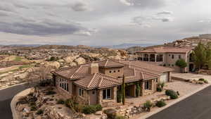 View of front of house featuring stone siding, a chimney, stucco siding, a mountain view, and driveway