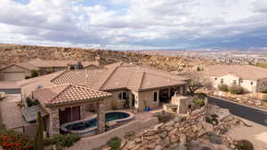 Back of house with a patio, stone siding, a tile roof, and a residential view