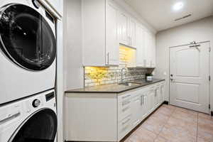 Laundry area with stacked washer and dryer and light tile patterned floors