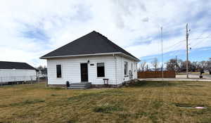 Rear view of house featuring roof with shingles and a gate