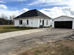 View of front of property with roof with shingles, an outdoor structure, a detached garage, and a front yard