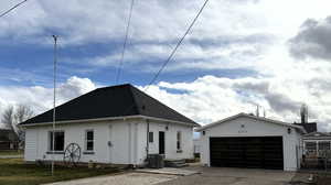 View of front of property featuring an outbuilding and a shingled roof