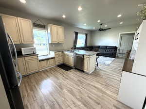 Kitchen featuring a kitchen breakfast bar, a peninsula, stainless steel appliances, light wood-type flooring, and recessed lighting