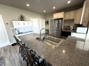 Kitchen with stainless steel appliances, a breakfast bar area, recessed lighting, a peninsula, and dark stone countertops