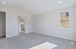 Unfurnished bedroom with vaulted ceiling, light carpet, recessed lighting, and connected bathroom