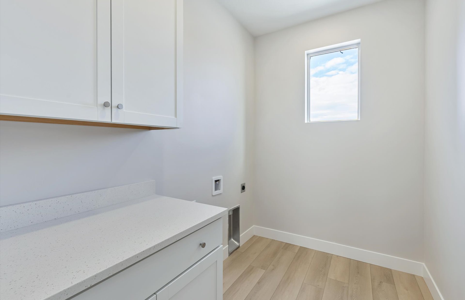 Laundry area featuring light wood-type flooring, electric dryer hookup, and cabinet space