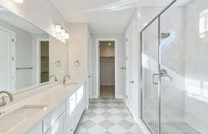 Bathroom featuring double vanity, a stall shower, a spacious closet, and light flooring